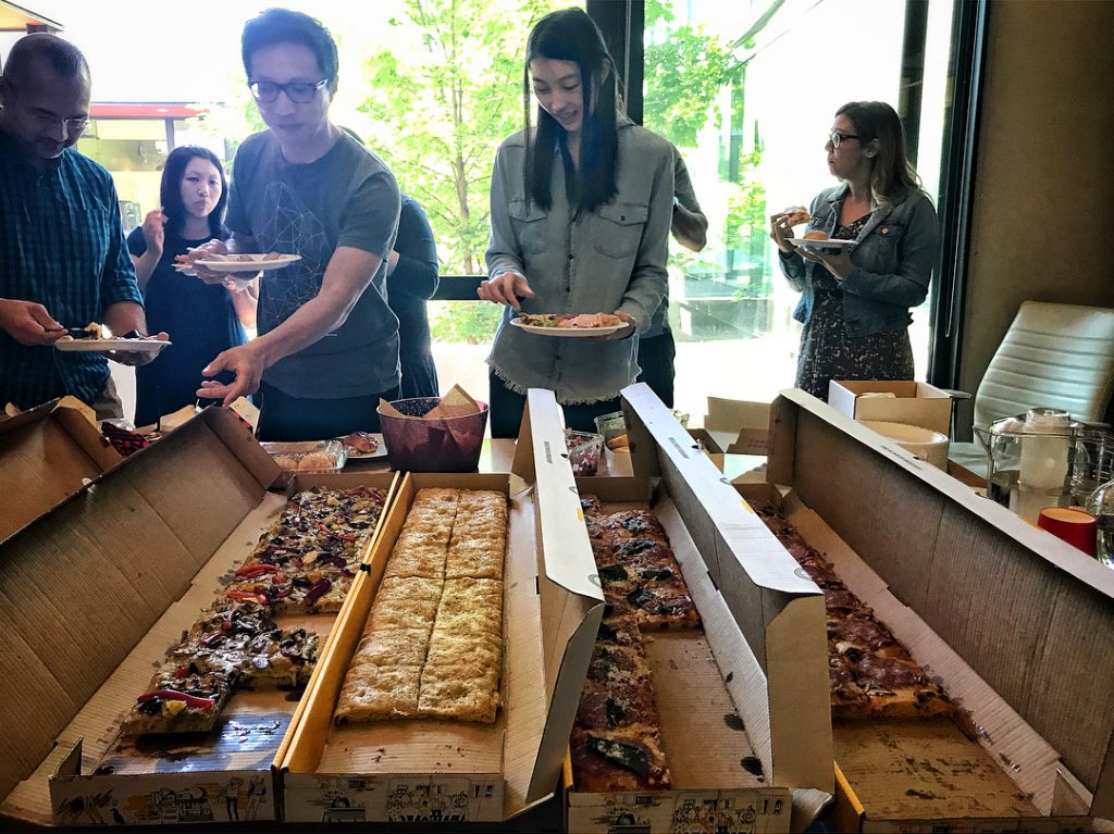OXD team members lining up for a pizza lunch buffet