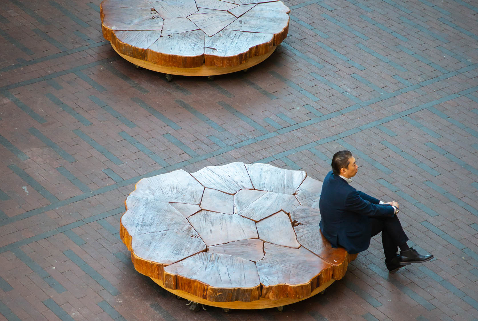 Man in full suit sitting on a wood bench for Management Consulting