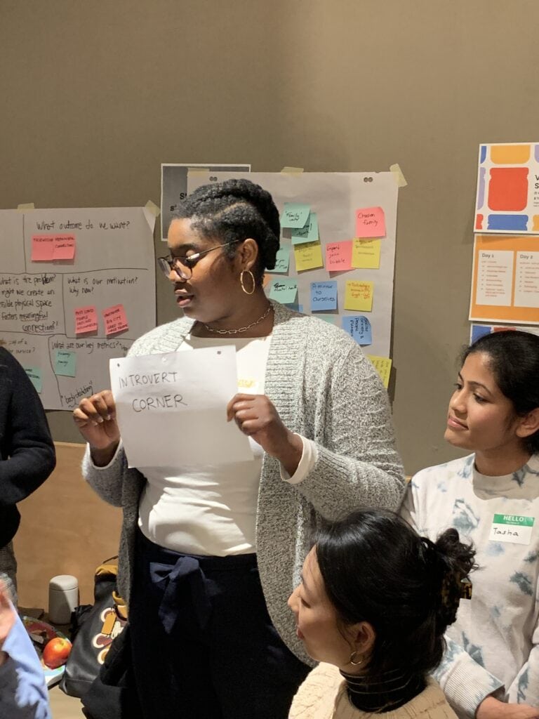 A person holding at paper saying Introvert Corner in front of sticky notes at Vancouver Service Jam