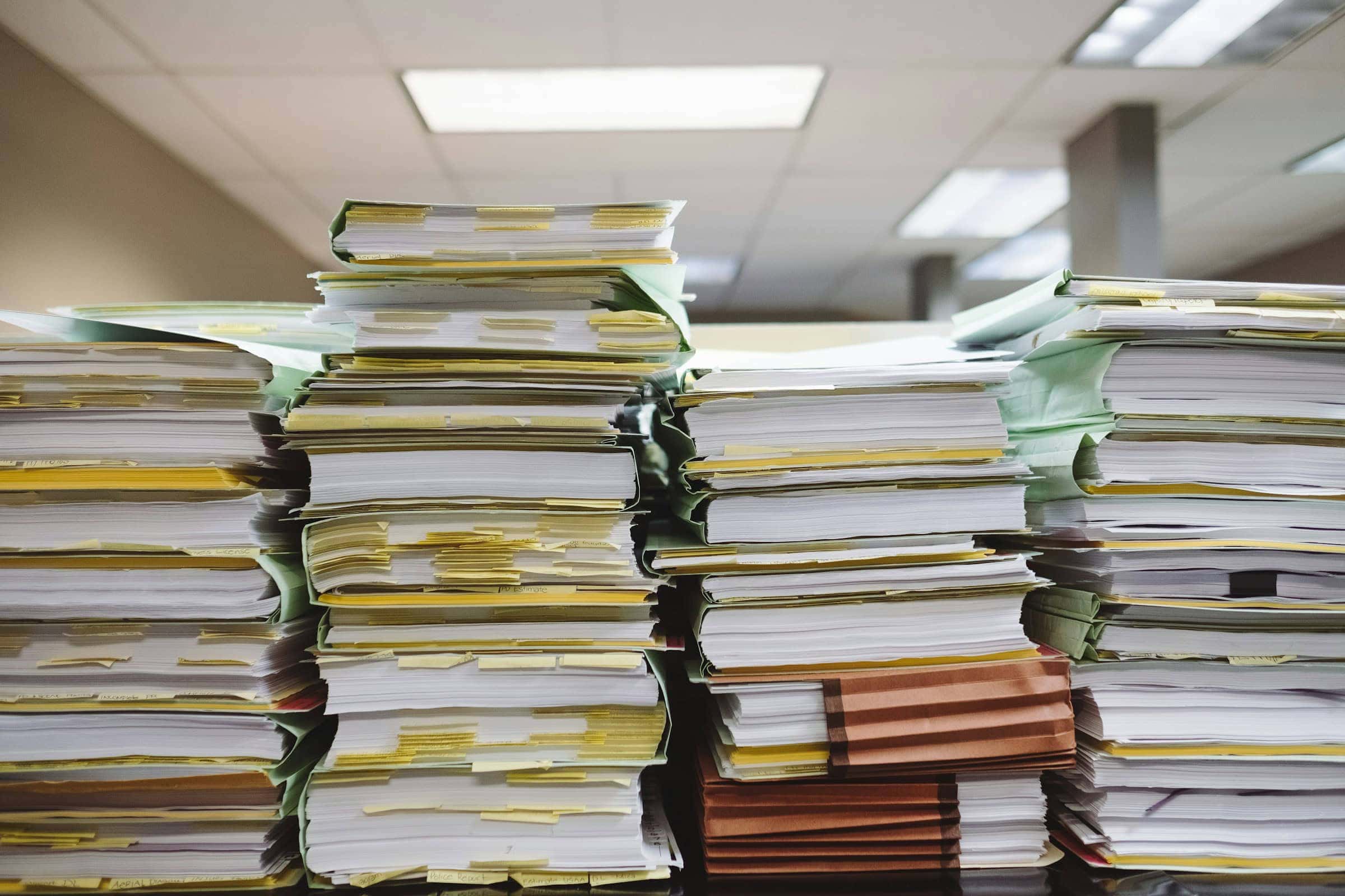 Photo of piles of files on a desk representing old paper processes before court modernization